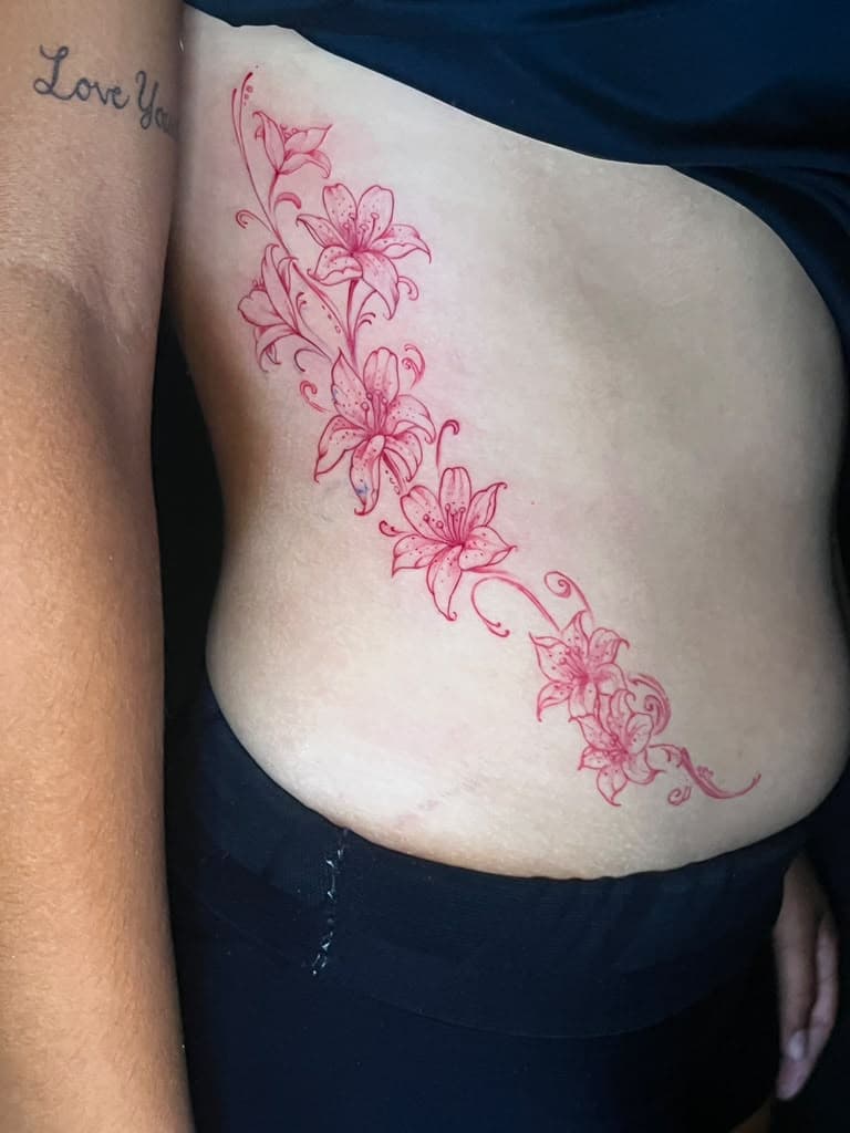 Red fine line lily vine tattoo along the ribs by Alison at Inked City Tattoos in Trenton, NJ