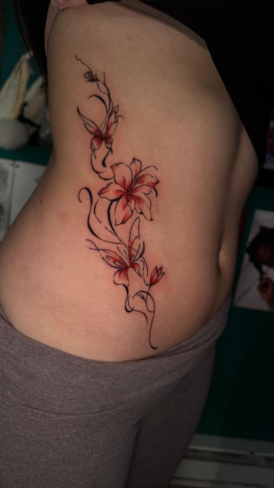 Red and black fine line lily vine tattoo on the side by Alison at Inked City Tattoos in Trenton, NJ