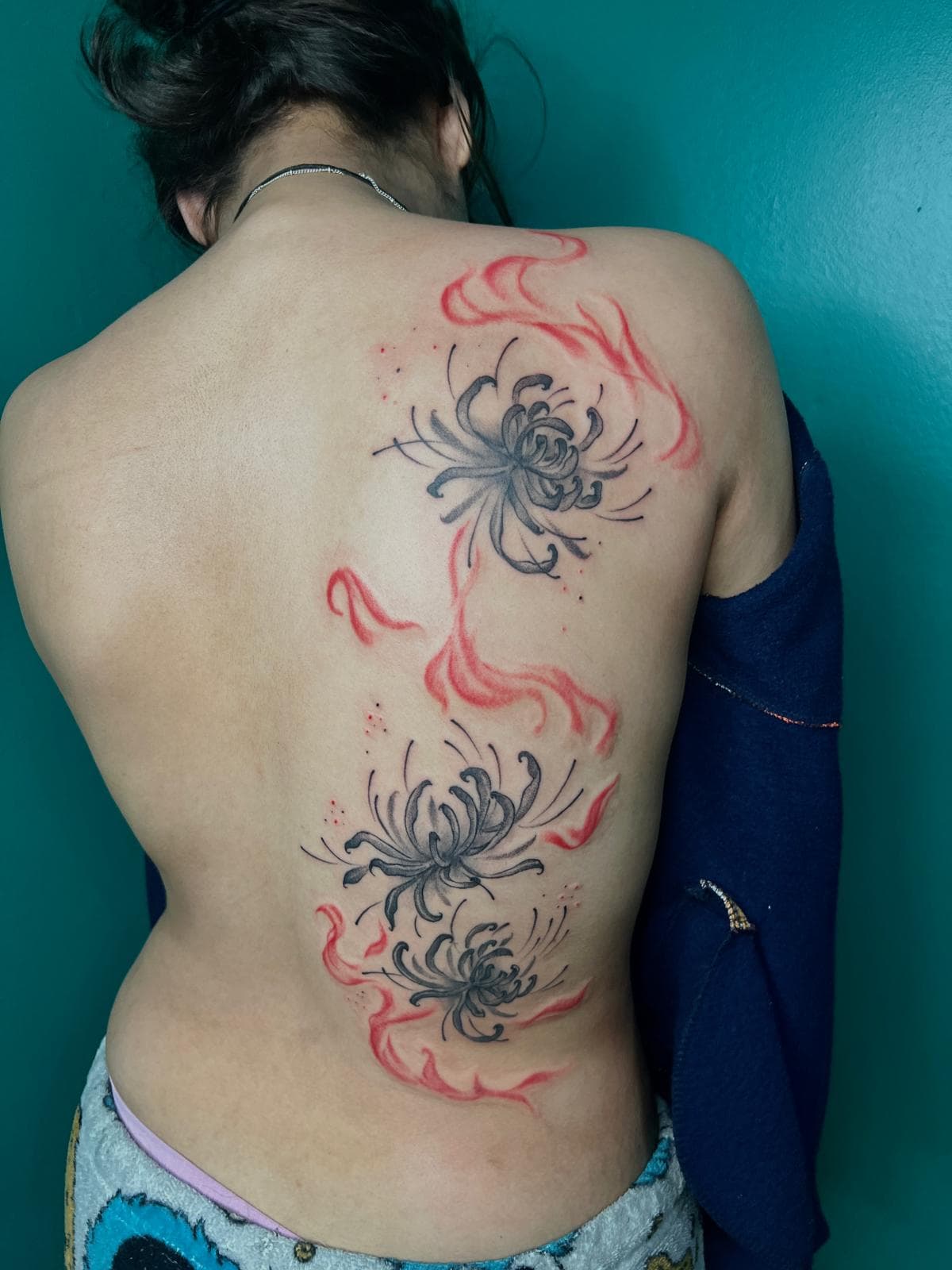 Red and black fine line spider lily tattoo down the back by Alison at Inked City Tattoos in Trenton, NJ